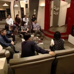 A group of people sitting in a living room watching television together.